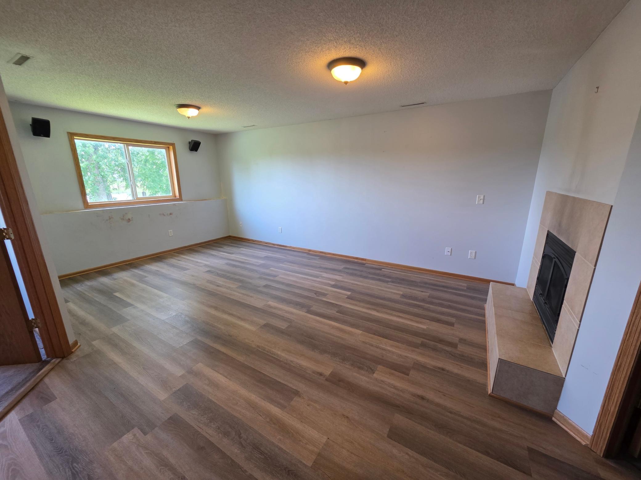 Finished lower-level family room with updated flooring, a fireplace, and plenty of room to relax or entertain.