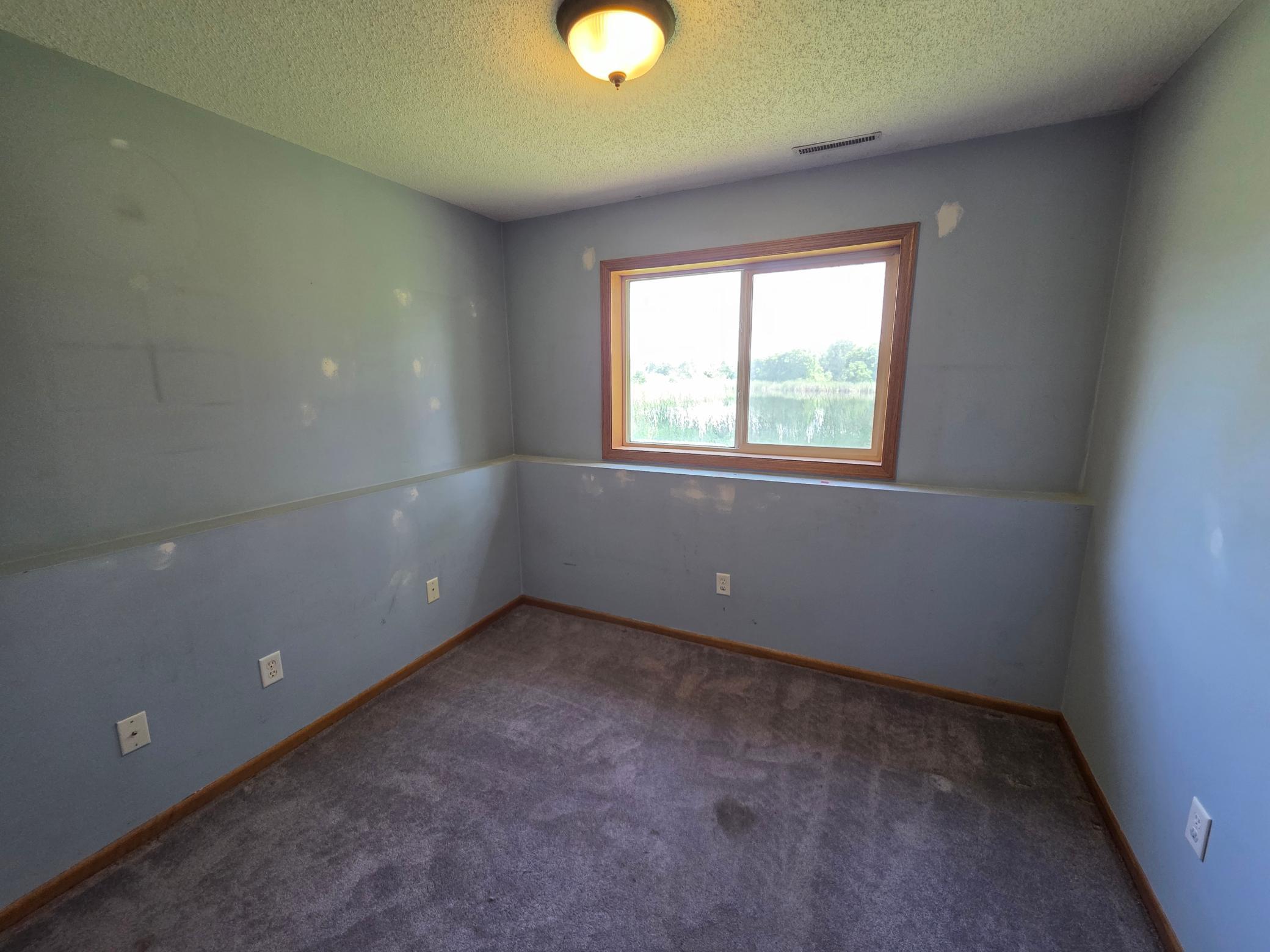 Additional bedroom with peaceful pond views and opportunity for fresh paint and personalization.