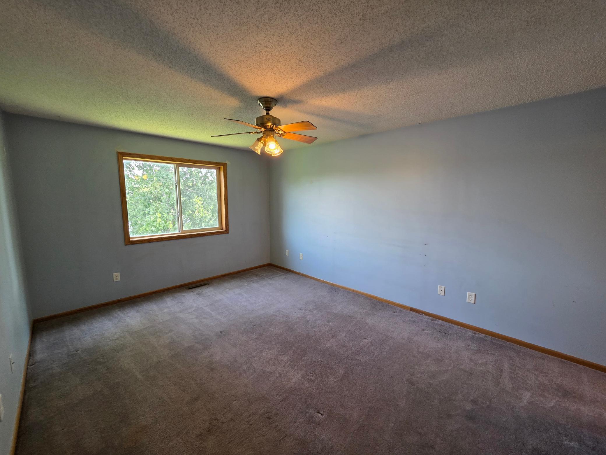 Bright upper-level bedroom with a ceiling fan, a large window, and comfortable proportions.