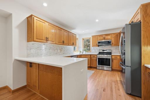 The kitchen has been remodeled to showcase beautiful quartz countertops with a waterfall edge and tile backsplash.