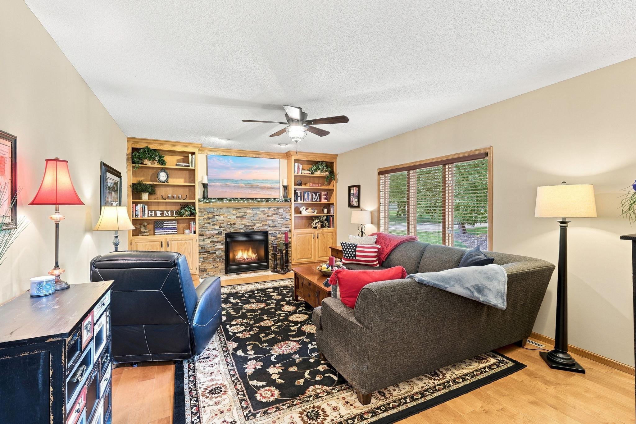Main level family room with a newly refinished stone surround gas fireplace with built-in bookshelves.