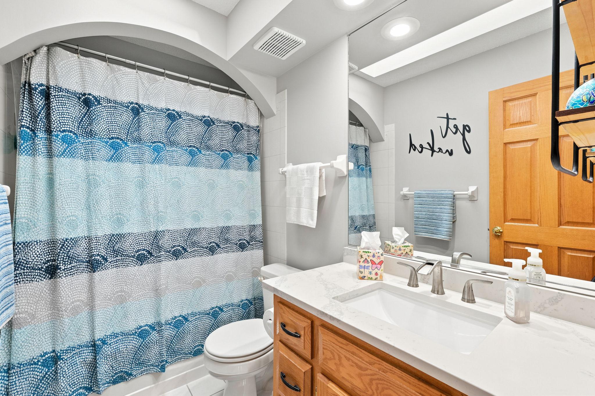 Upper level shared full bath with a skylight and granite counters.