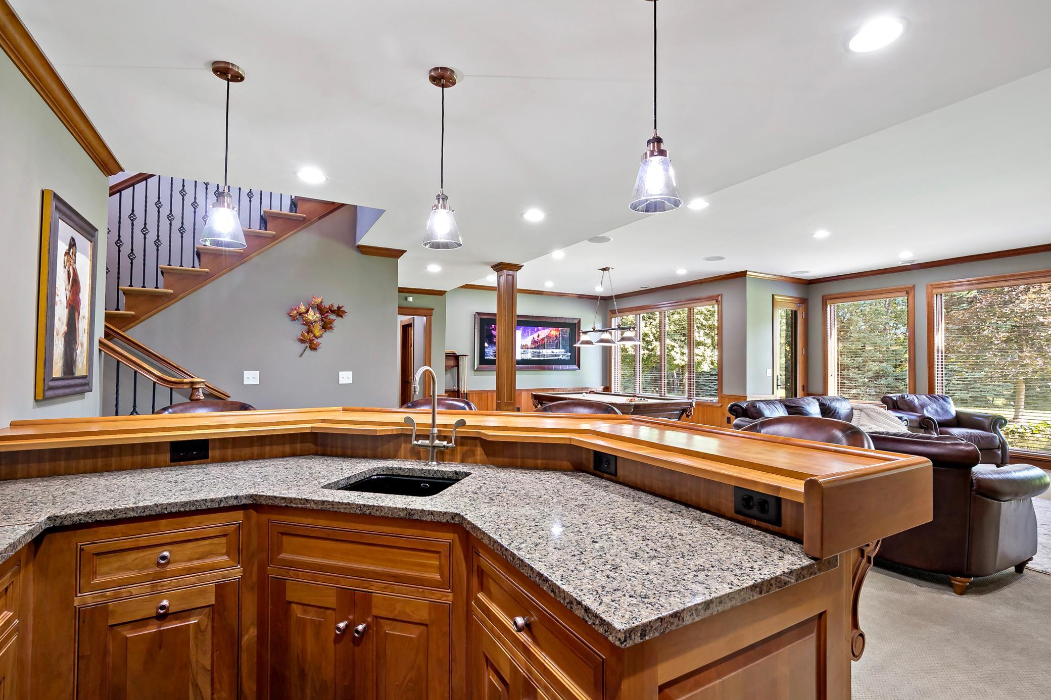 An entertainer's dream featuring a spacious walkout lower level, handcrafted stonework, full wet bar, and dedicated recreation area.