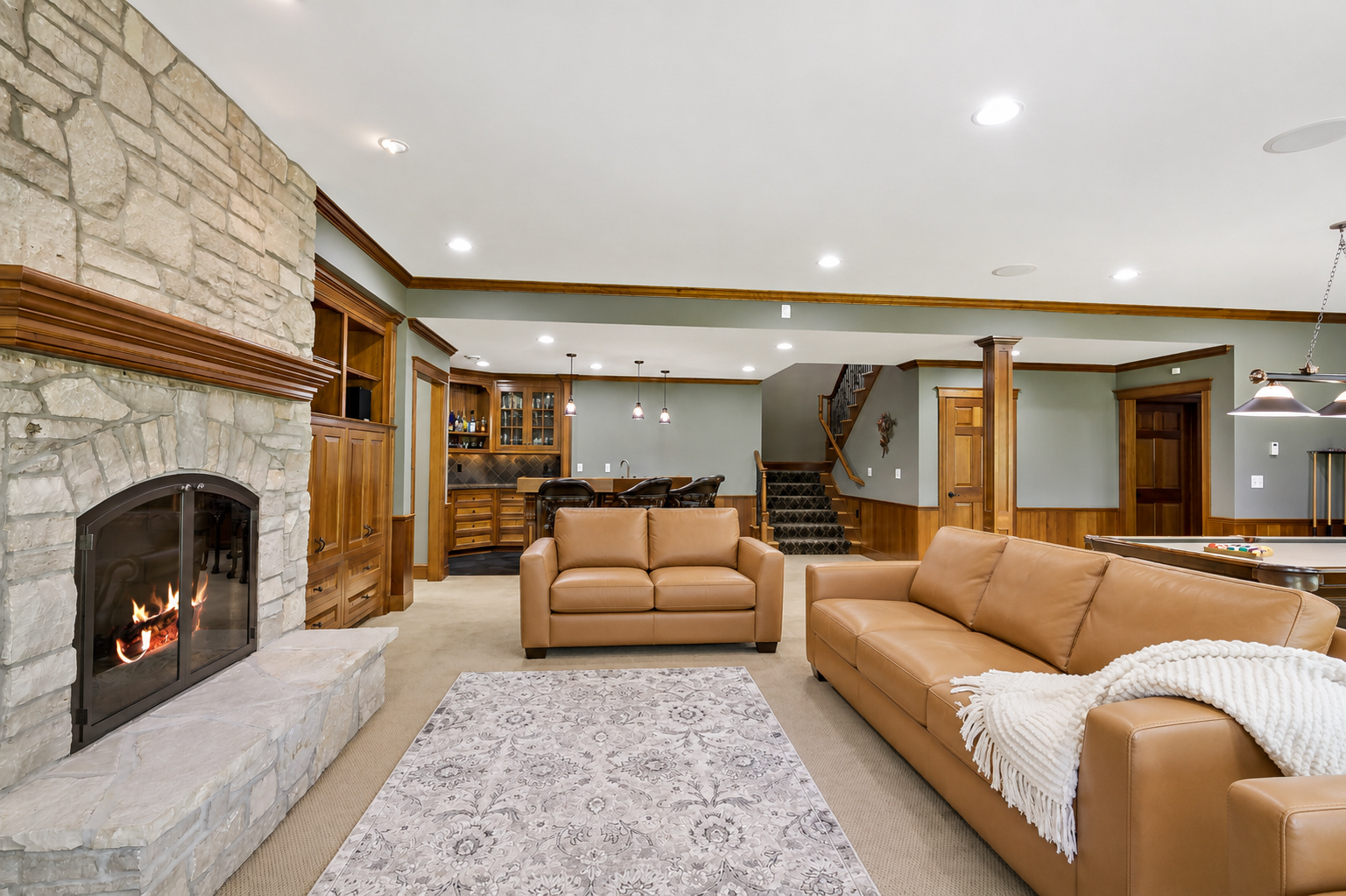 Spectacular walkout lower level designed for entertaining, featuring custom stonework, a full wet bar, and expansive gathering spaces.