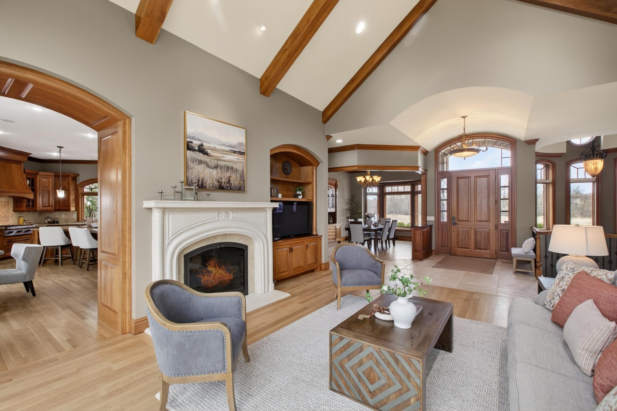 The grand living room features a dramatic floor-to-ceiling stone gas fireplace shared with the kitchen, creating a warm centerpiece for everyday living. Brand new hardwood flooring!