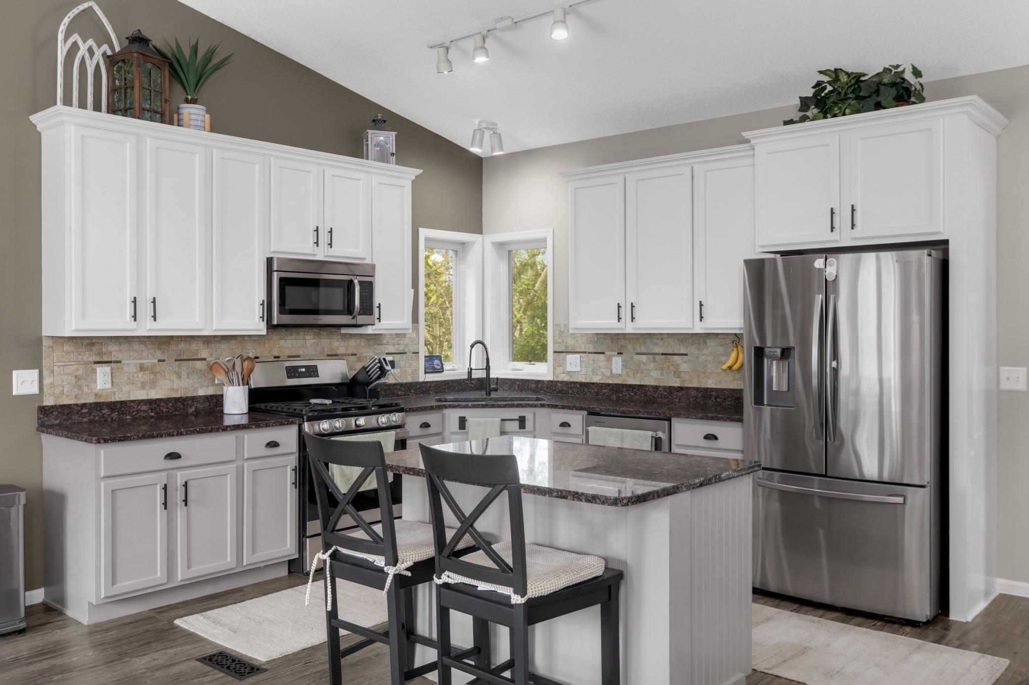Beautiful kitchen featuring white cabinetry, granite countertops, and peaceful backyard views.