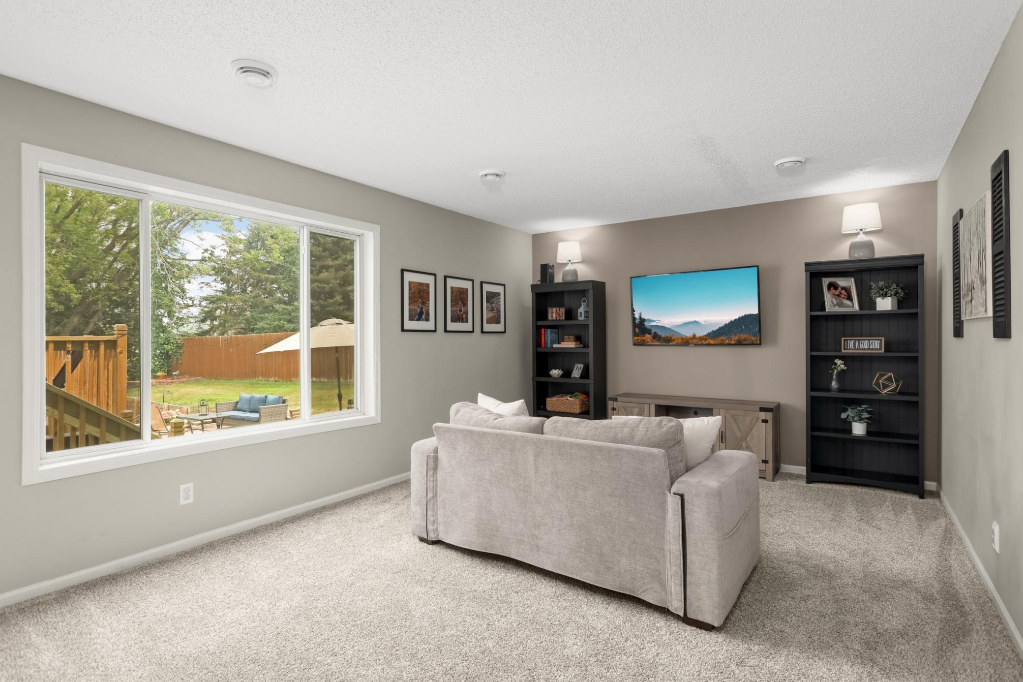 Spacious living room with large windows overlooking the serene backyard.