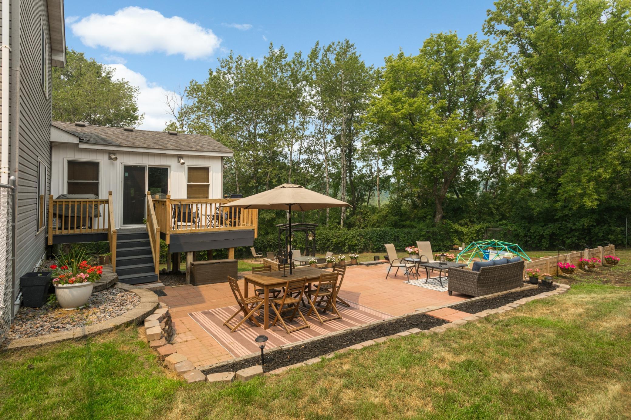 Private backyard oasis featuring a newly built deck, two brick patios, and newly installed retaining walls.