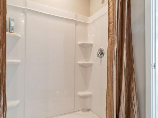 Walk-in shower with shelving in the primary bathroom.