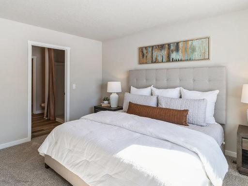 Bedroom suite with bed and nightstands with view of private bathroom.