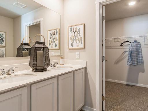 Bedroom suite's bathroom with large mirror and white cabinetry.