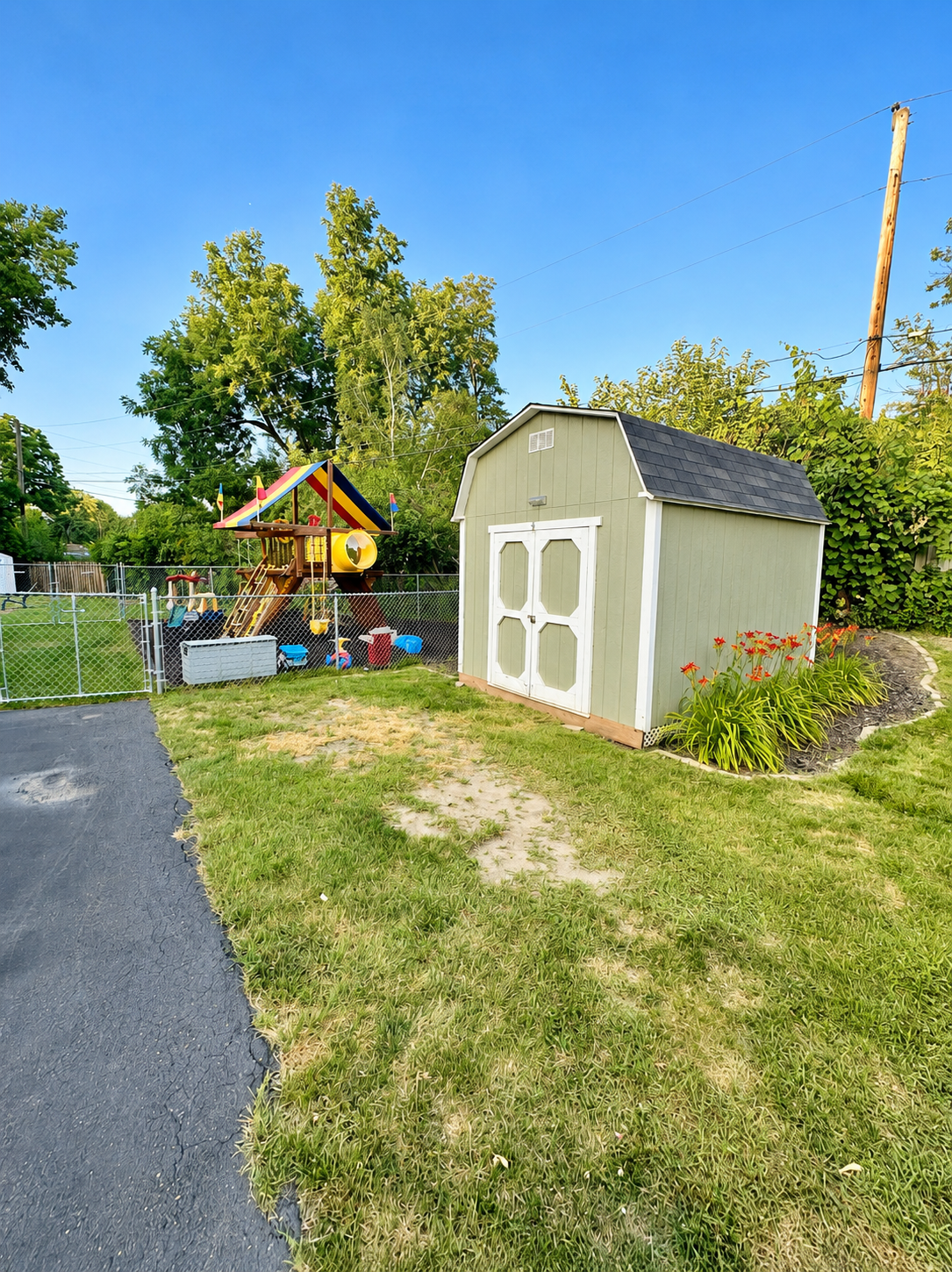 Large storage shed and asphalt parking pad on side of the garage