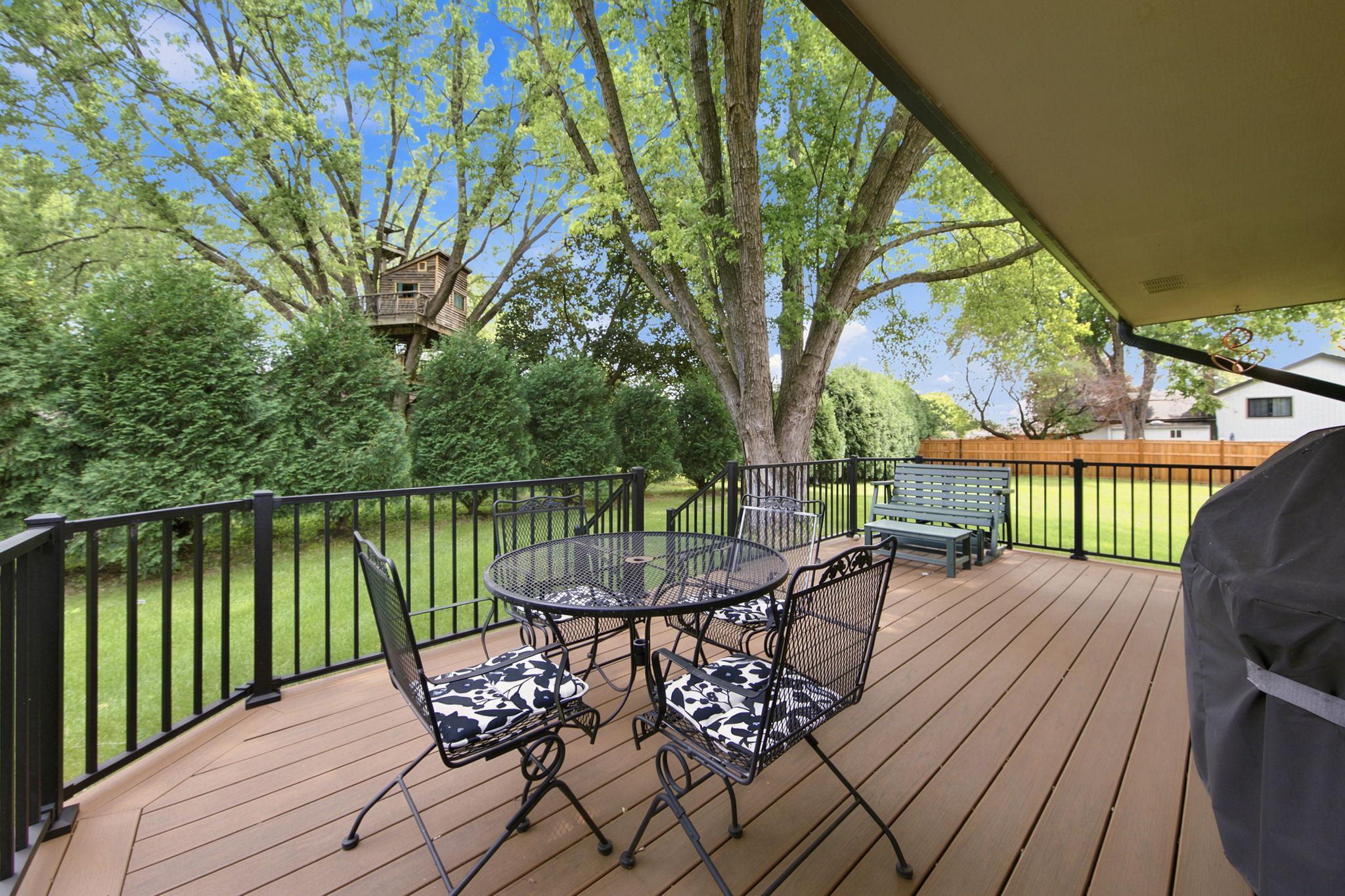 Trex deck overlooking a green lawn and trees lining the back of the property!