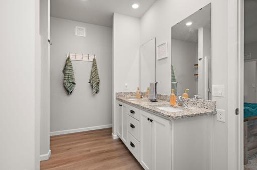 Primary suite with double vanity sink, granite countertops, a large soaker tub, and a separate walk-in shower