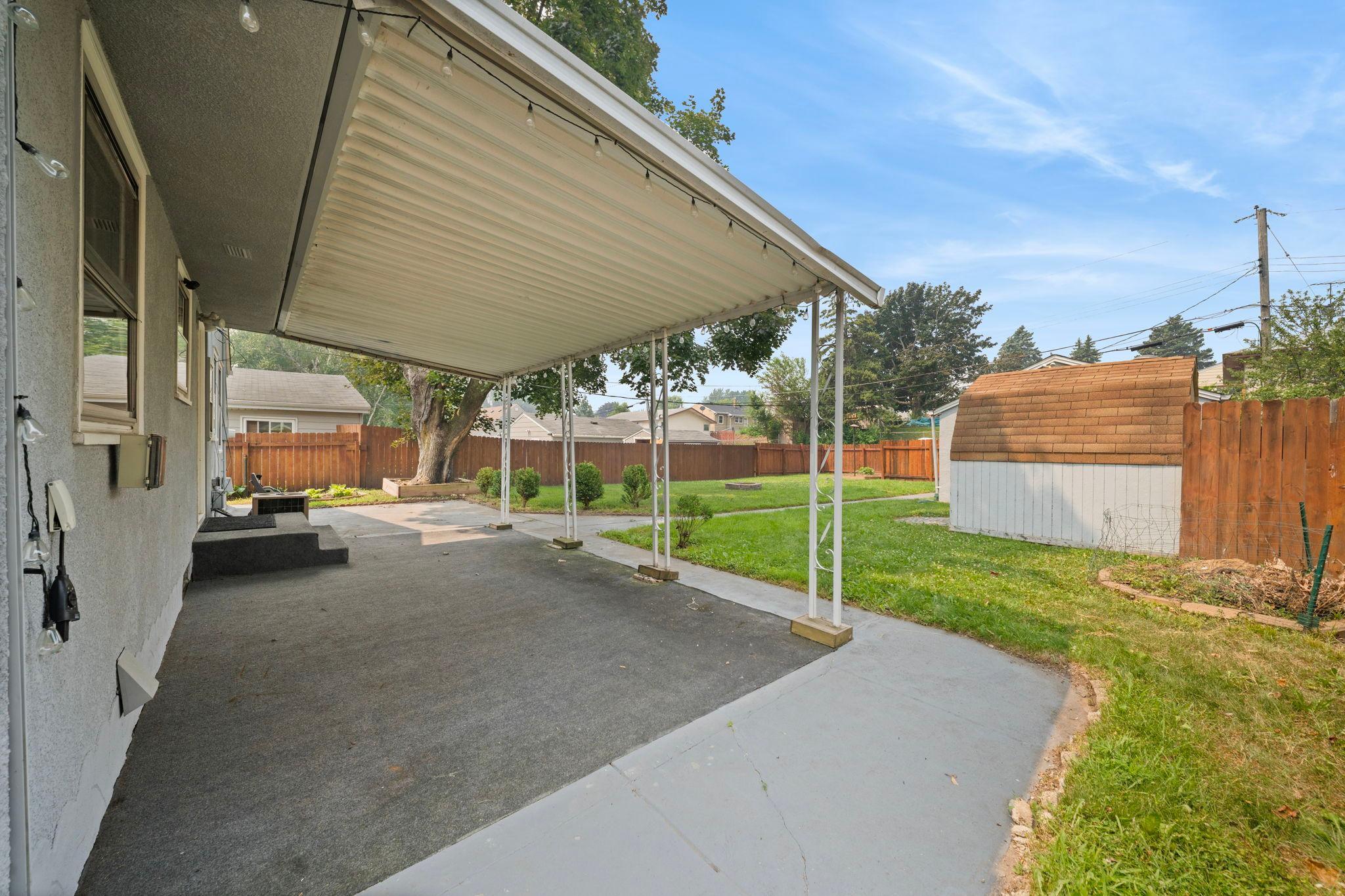 A covered patio stretching toward a fully fenced backyard. String the lights, pull up a chair, let the evening go long.
