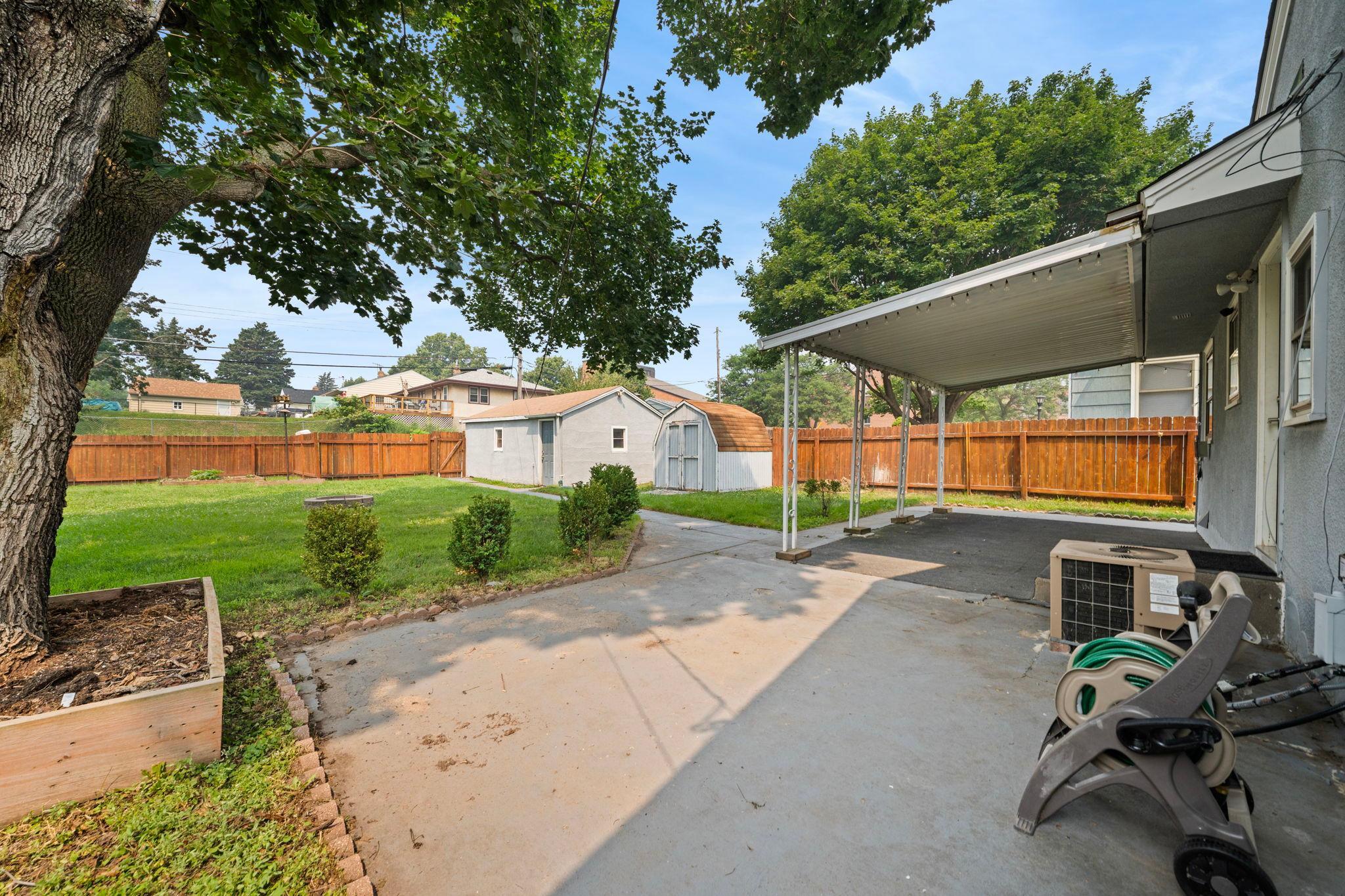 A backyard with a patio, a storage shed, and green space that goes on and on. Room for the garden hose, the bikes, and every summer plan.