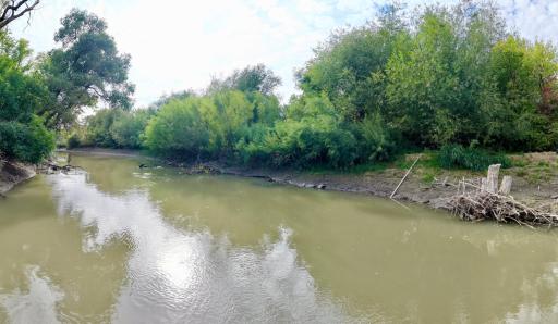 Sheyenne River frontage with the lawn irrigation pump hose visible along the bank