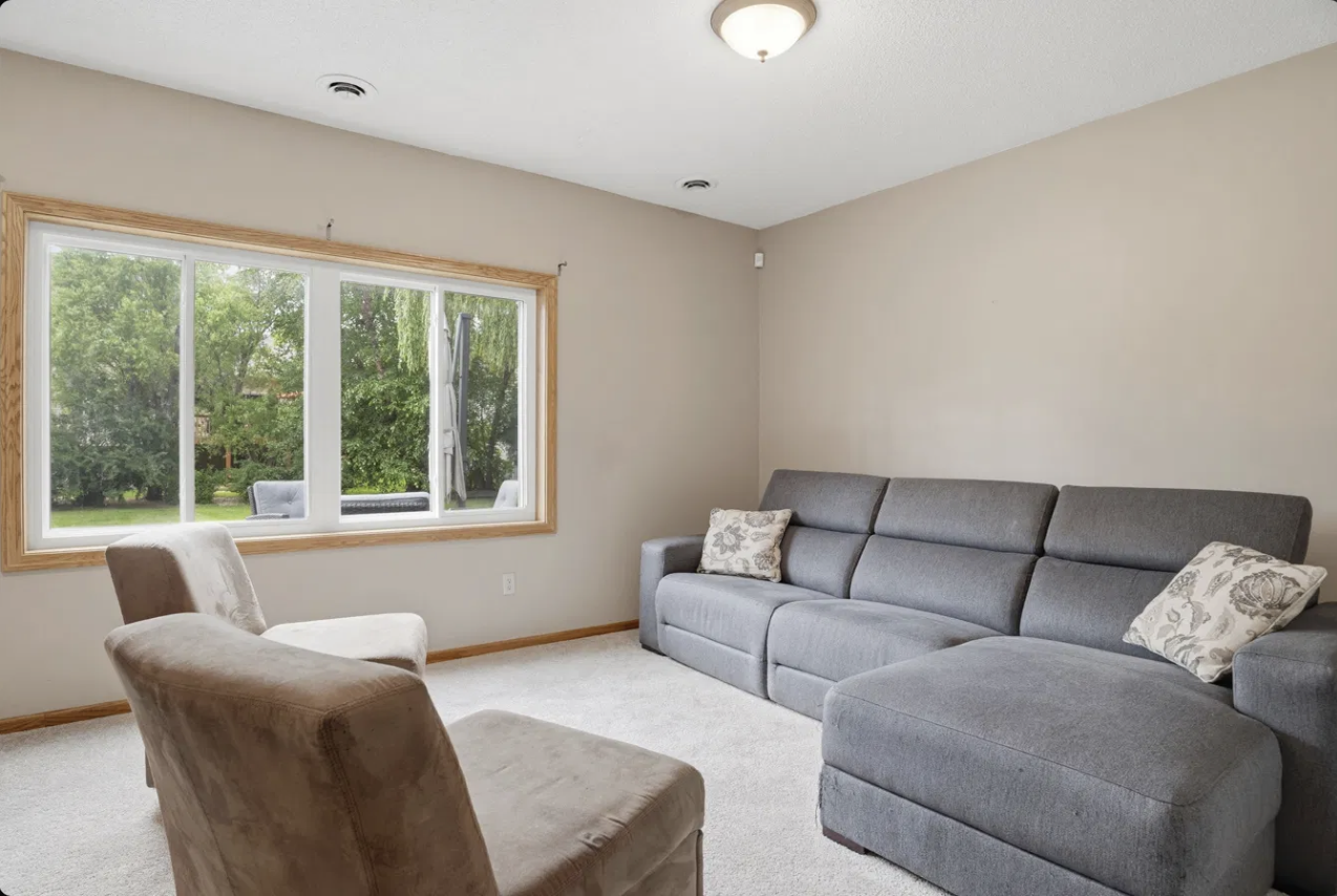 Unwind in this bright lower level family room, where a wall of windows frames the patio and backyard, and a deep sectional invites you to settle in for movie nights, game days, or quiet evenings at home.