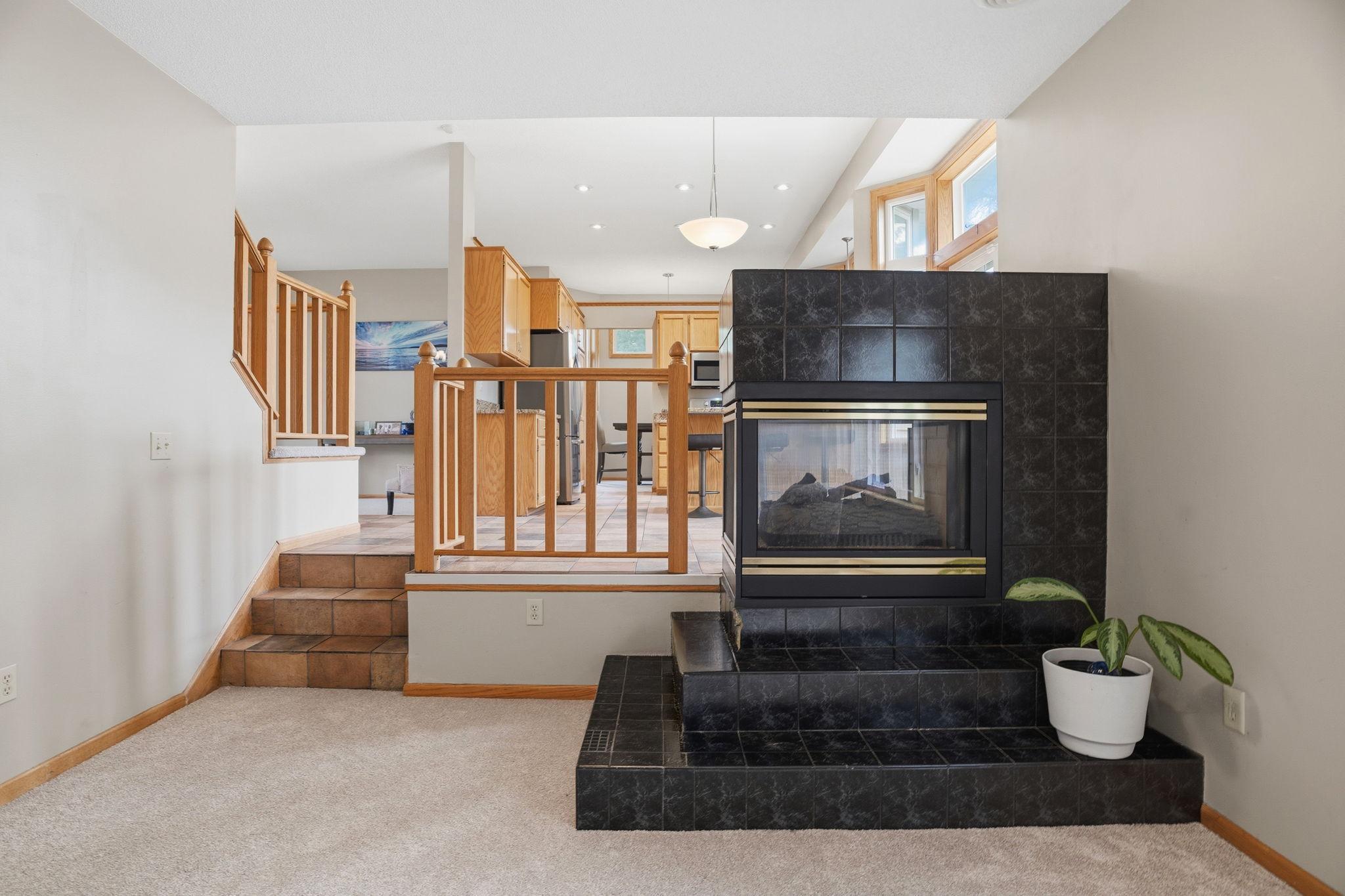 From the sunken family room, tiled steps climb past a dramatic fireplace to the open kitchen above, a layout that keeps everyone connected while entertaining.