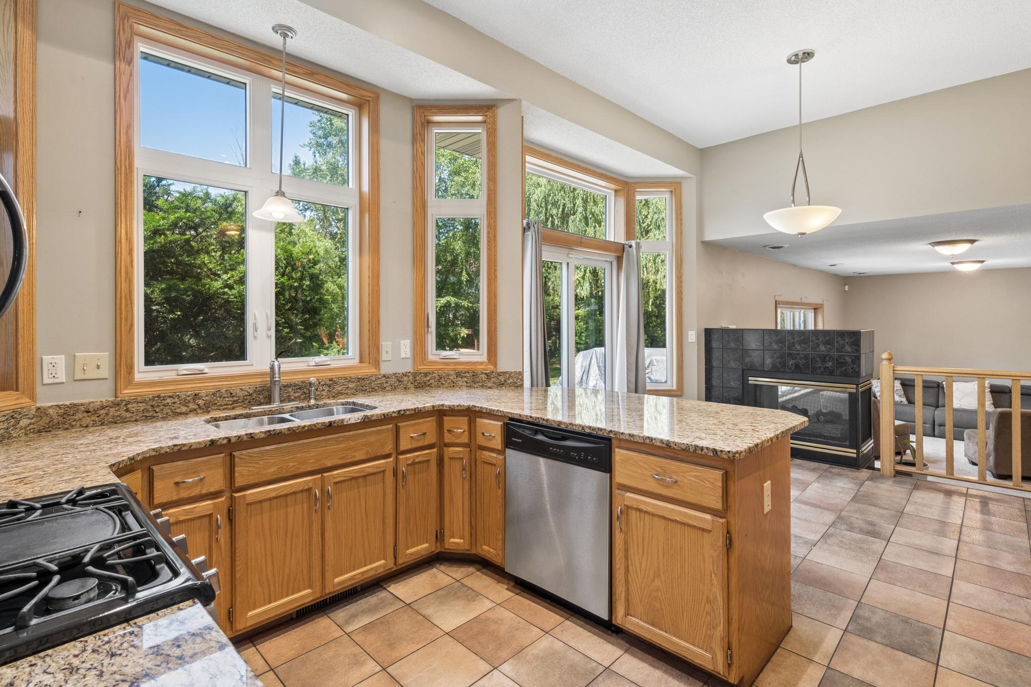 Granite stretches corner to corner. The gas range faces the backyard. Every surface catches the light. And somewhere past the counter, the fireplace waits. This kitchen was built for real cooking and real living.