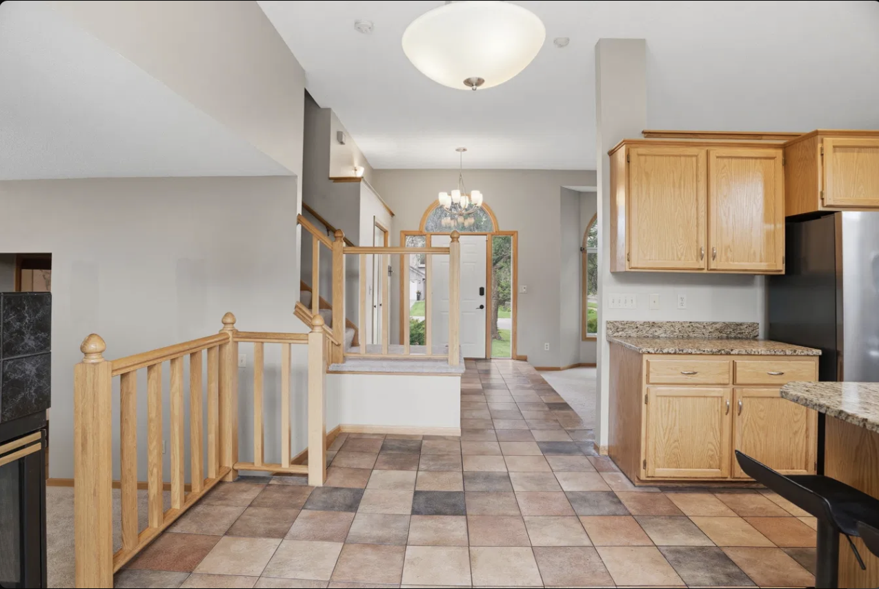 Warm tile floors anchor this informal dining space, open to the kitchen just steps away and flowing effortlessly into the living room beyond, an easy gathering spot for everyday meals with the staircase rising nearby.