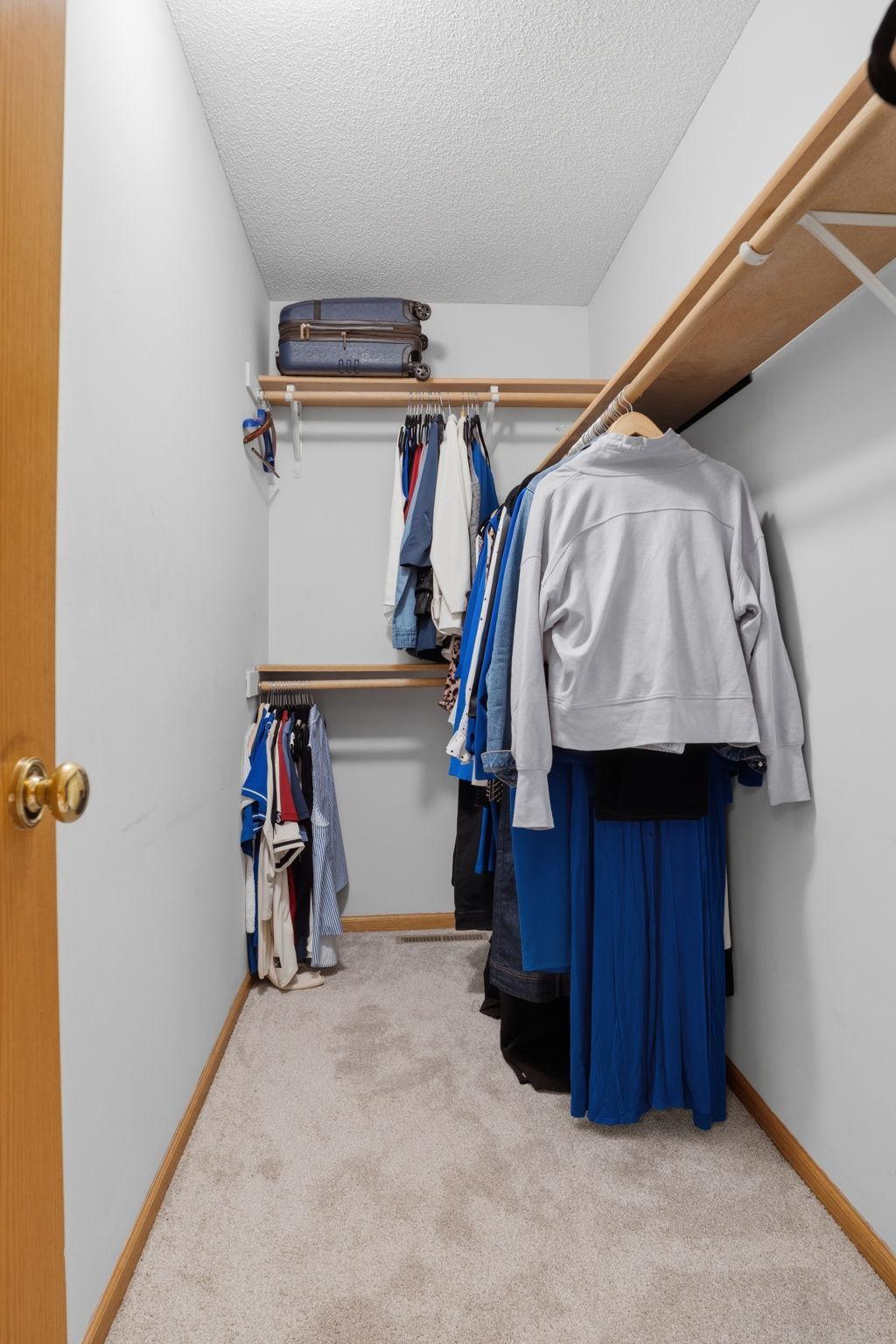 Double hung rods and a long run of shelving make this primary walk in closet a true dressing room, plenty of space to keep every wardrobe organized.
