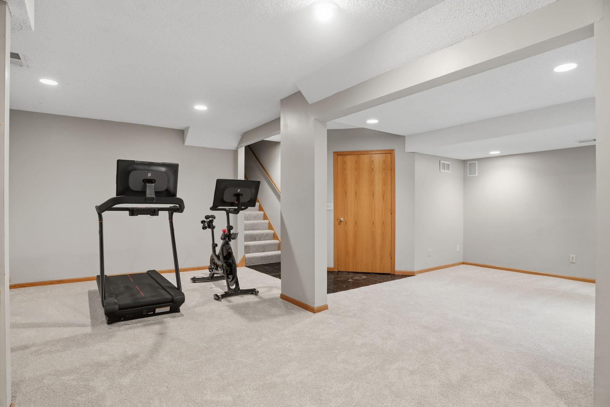 Recessed lighting overhead. Fresh carpet underfoot. An open footprint that runs the length of the room with a clear path to the stairs. However you fill it, the space is already here.