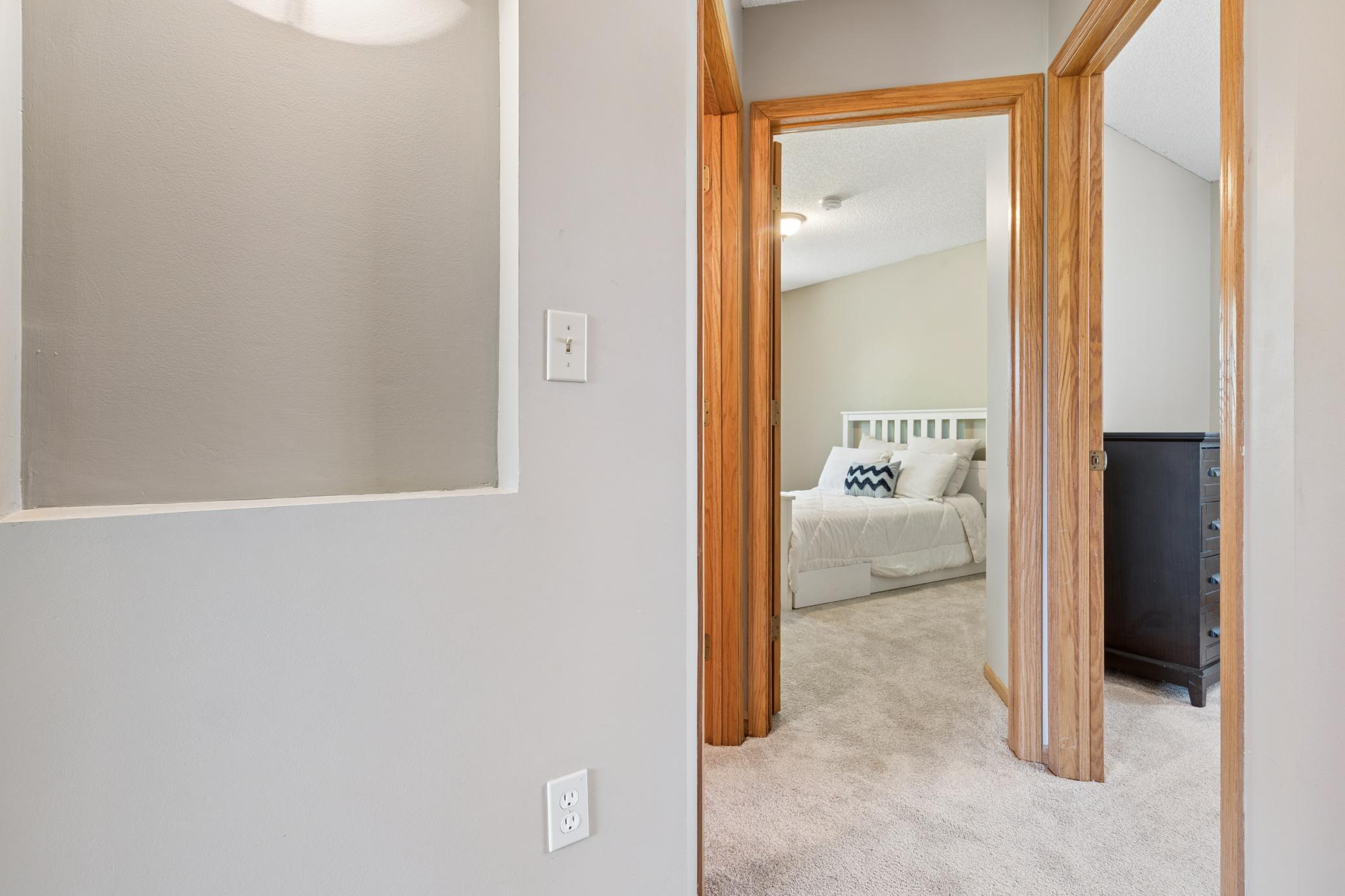 The hallway connects the bedrooms without crowding them. Each door is its own world. The carpet runs soft underfoot. This is the quiet corridor where the day begins and ends.