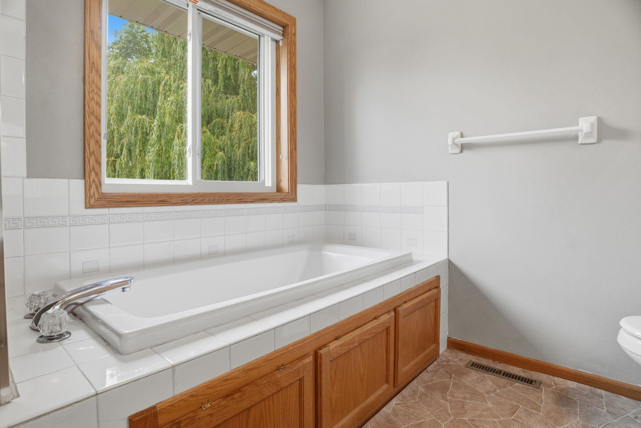Soak away the day in the primary bath's deep tub, framed by a window overlooking swaying willow branches for a private, spa like escape.