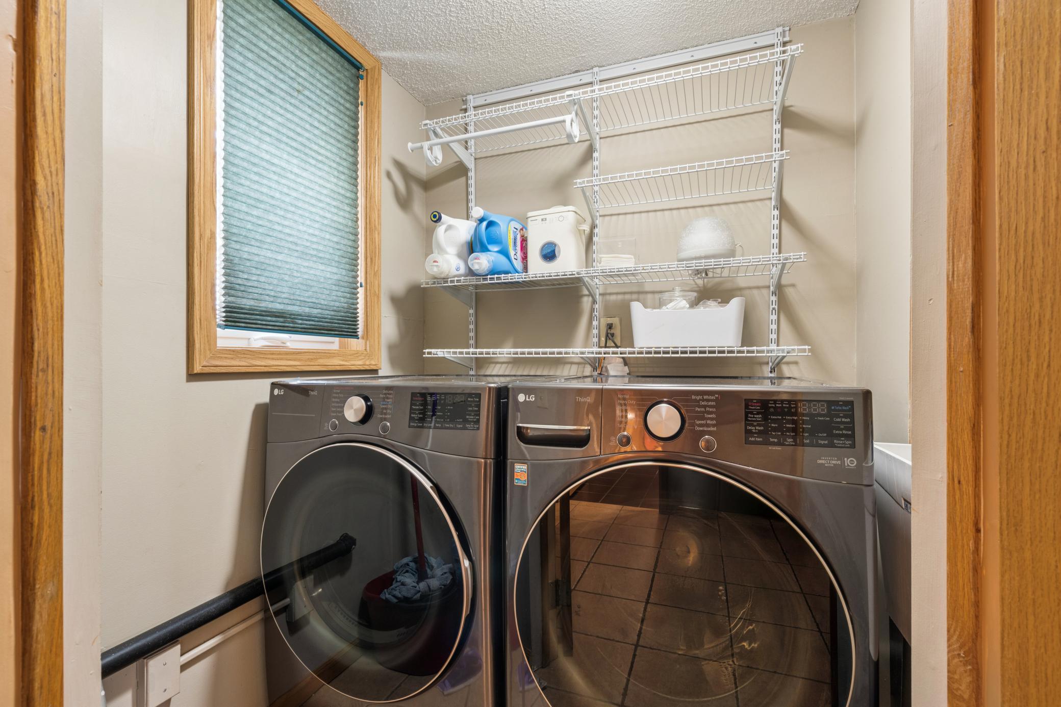 The laundry room on the main level with LG front-loaders and layered wire shelving that actually keeps up with the household. Natural light, real storage, and a setup that makes the routine feel less like a chore.