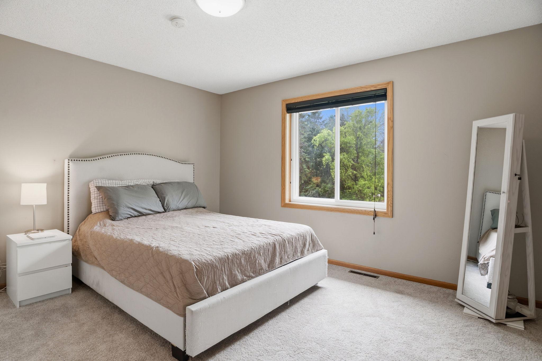 Treetops fill the window of this comfortable bedroom, a peaceful spot with room to spread out and easy access to the home's other living spaces.