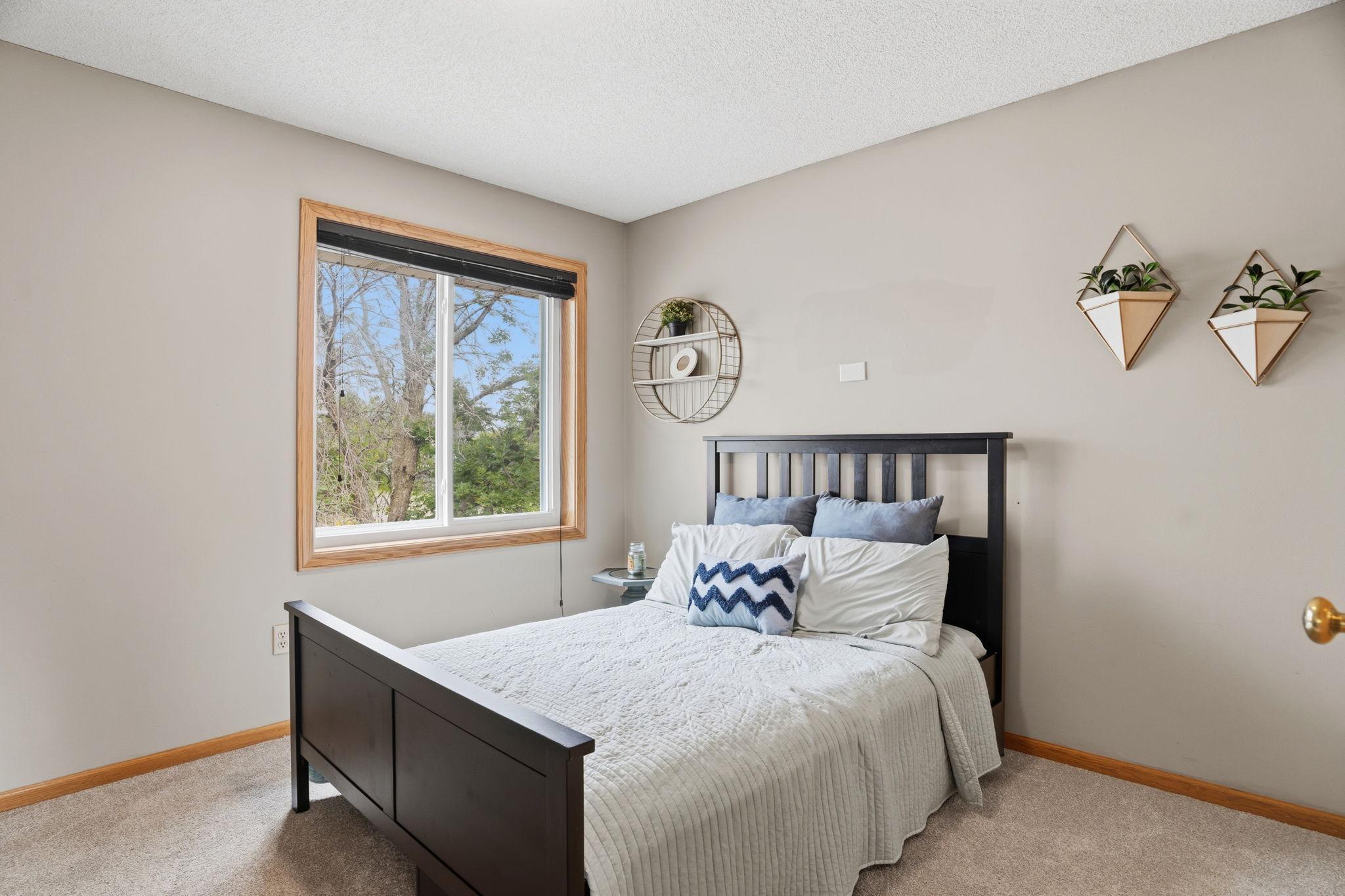 The third upper bedroom has personality already built in. Sage tones, dark wood furniture, a window with a view into the tree canopy. Light, grounded, and completely livable.