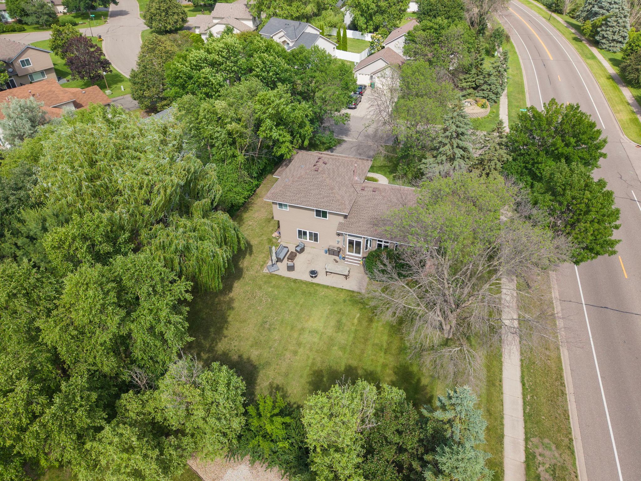 Straight down. The corner lot laid out in full. Trees on every edge. The patio visible off the back. A new roof catching the sun. This is what 13,000 square feet of corner lot looks like from the sky.