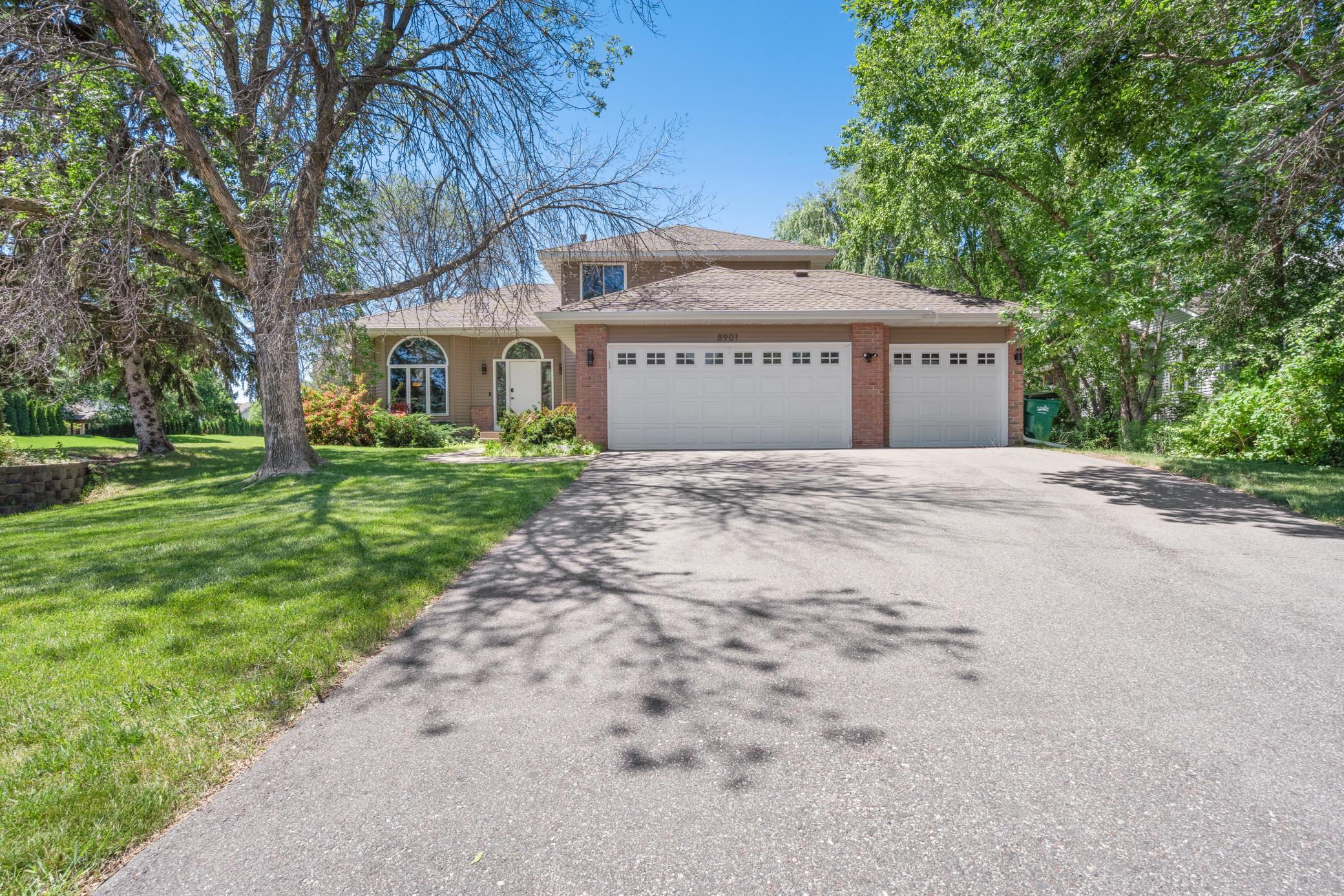 Mature trees frame the whole picture. Brick, new siding, three-car garage, and a driveway wide enough to mean it. From the street, this home signals exactly what it delivers: substance.