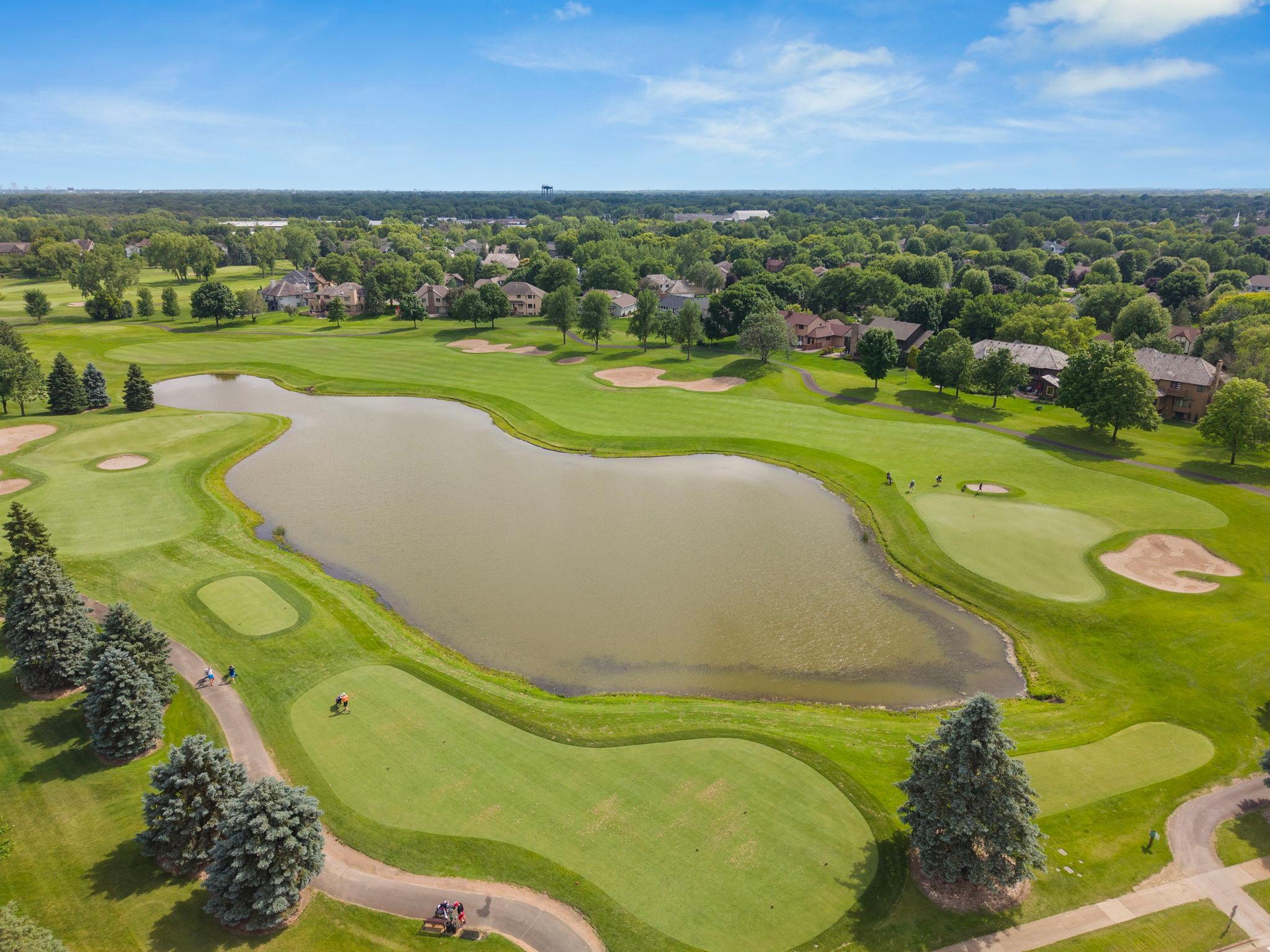 Fairways, sand traps, and a pond stretching wide under a blue Minnesota sky. This is the golf course just minutes from your front door. The views from up here make it clear why the location matters.