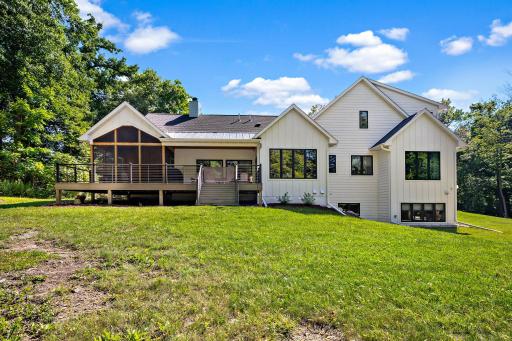 Rear elevation featuring 3-season porch, Trex surfaced deck and mini veranda. West facing for sunset watching inside or out with all those windows.