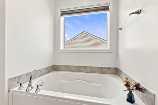 Luxurious soaking tub perfectly positioned beneath a beautiful picture window.
