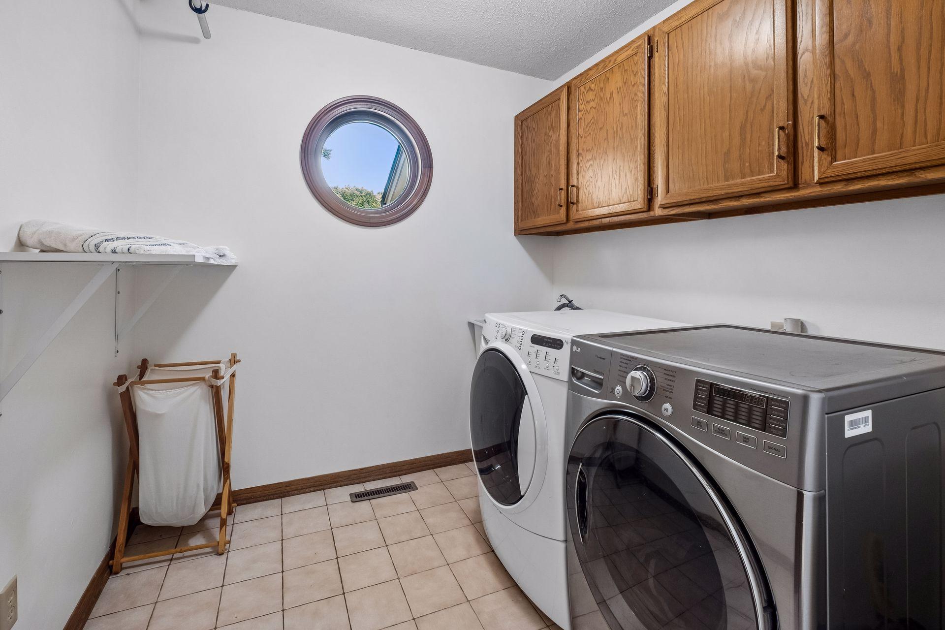 Main level laundry room with tile flooring and plenty of storage space.