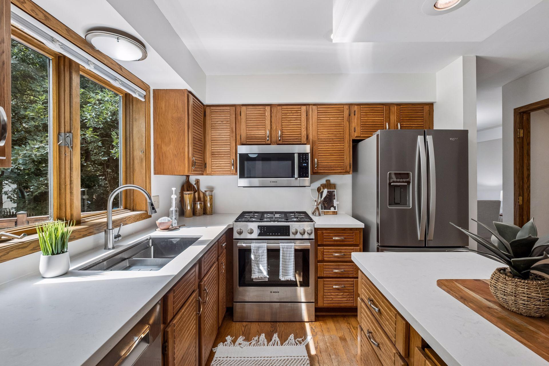 Newer Cambria countertops paired with updated cabinetry, stainless steel appliances, and hardwood flooring elevate this kitchen.
