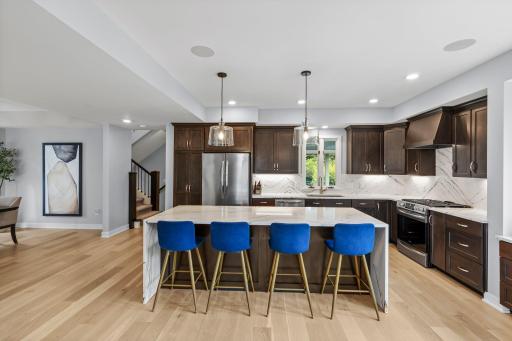 The oversized island anchors the kitchen with abundant seating, exceptional prep space and a refined mix of rich wood and dramatic quartz.