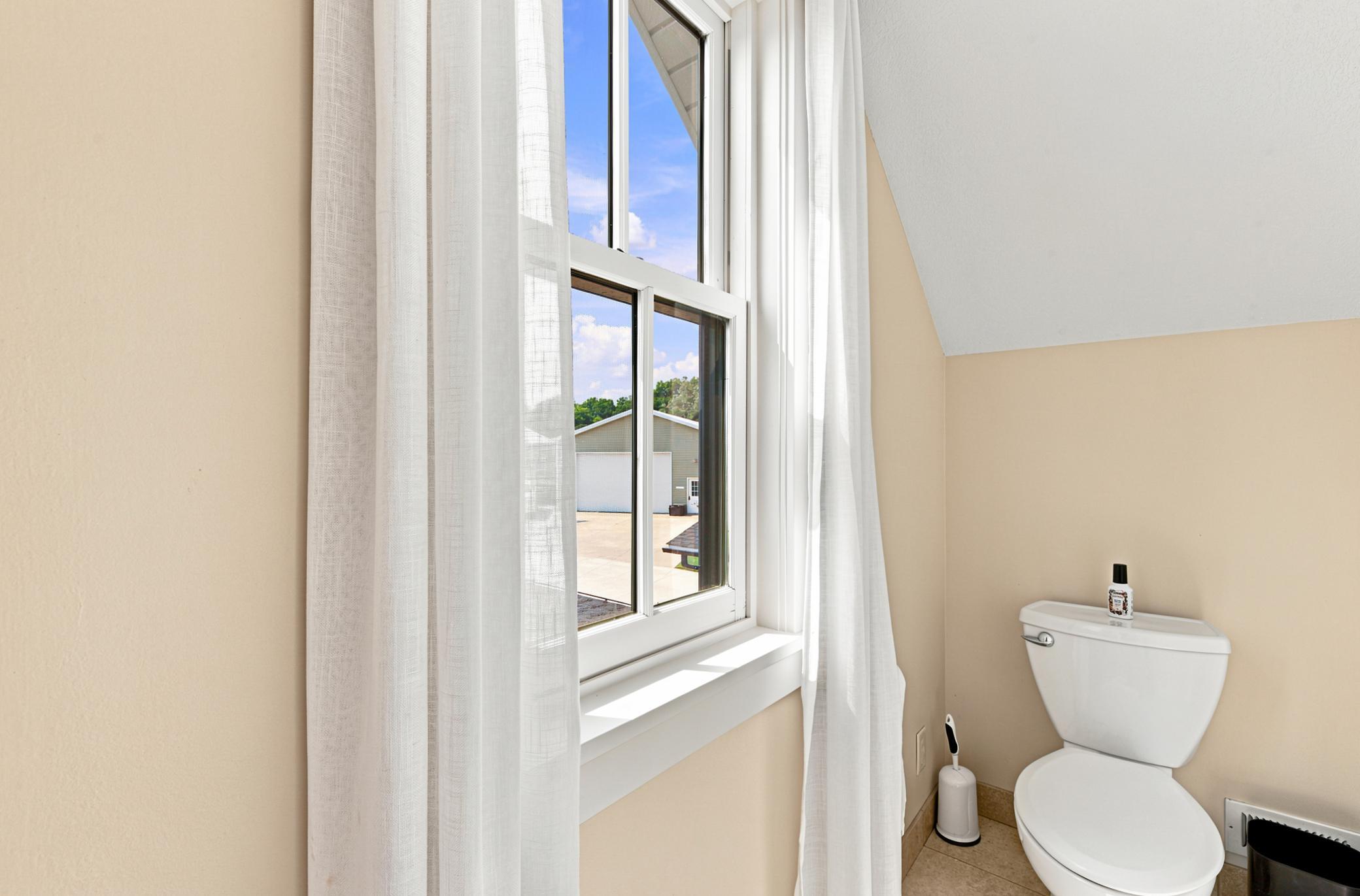 This luxurious bathroom serves both the main bedroom, second bedroom and the adjoining bonus space, featuring a double vanity with stone countertops, modern oval mirrors, a deep soaking tub, and a separate glass-enclosed tile shower.