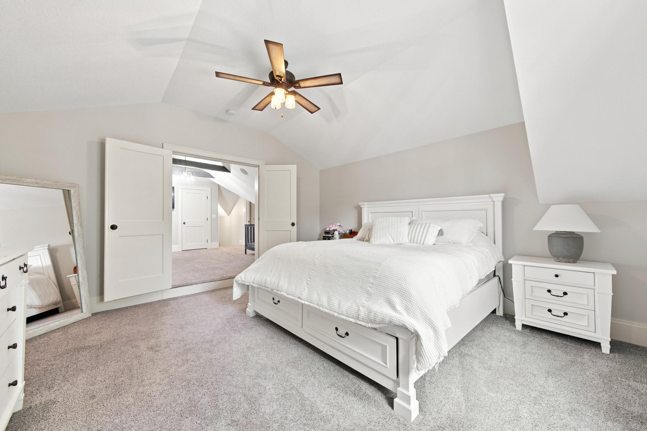 This sprawling primary suite offers an incredible bonus layout, with vaulted ceilings that connects seamlessly through elegant double doors to a private nursery or sitting room accented by rustic exposed beams.