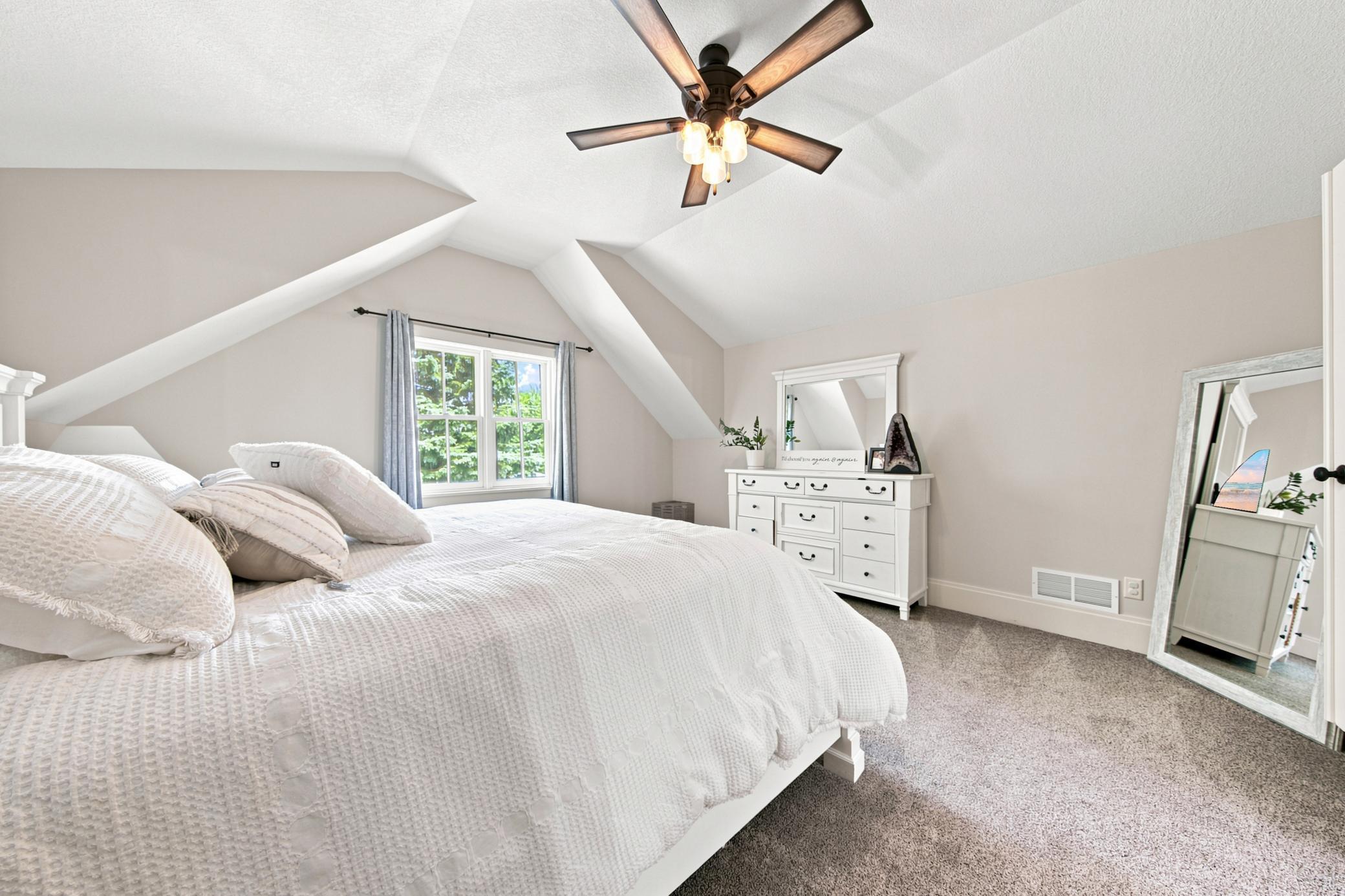 This sprawling primary suite offers an incredible bonus layout, with vaulted ceilings that connects seamlessly through elegant double doors to a private nursery or sitting room accented by rustic exposed beams.