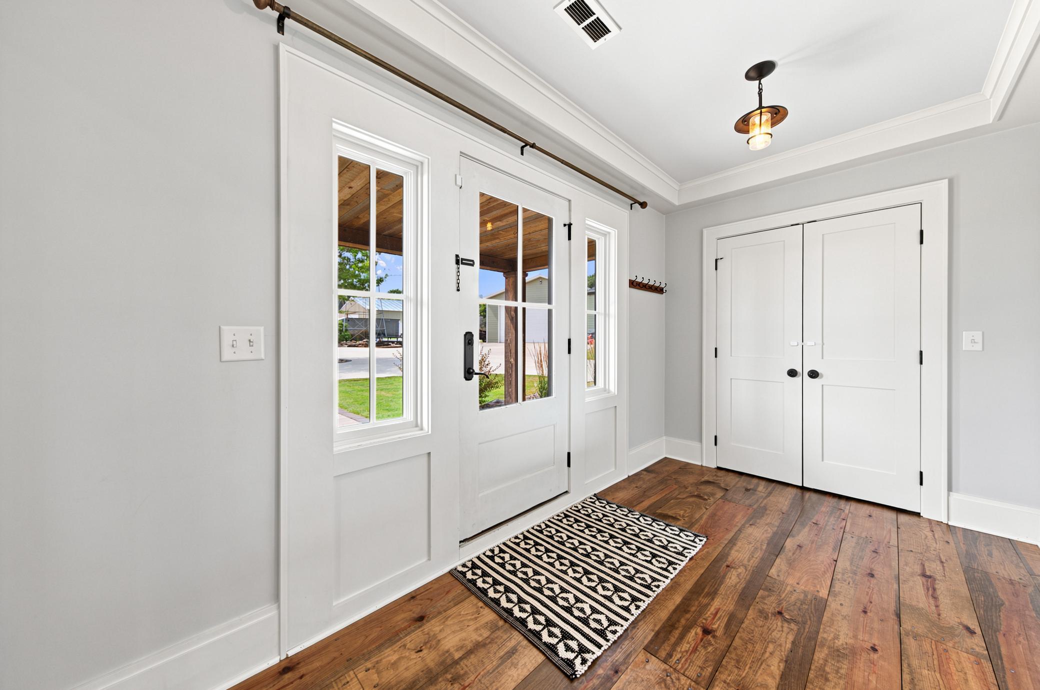 The bright foyer welcomes you with gorgeous wide-plank wood floors, a stylish glass-paneled front entry with matching sidelights, and a spacious double-door coat closet.