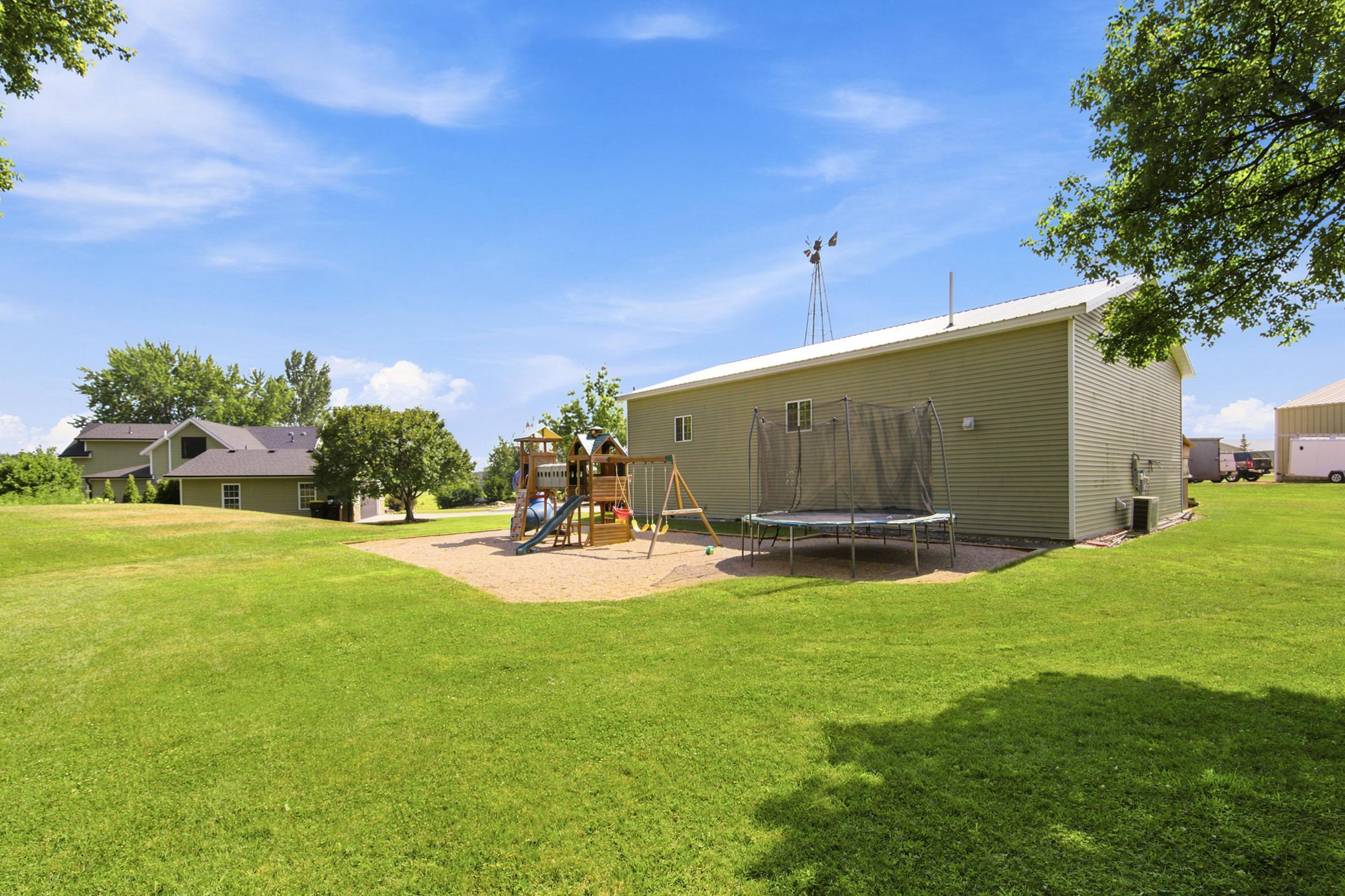 An expansive, park-like backyard offers endless outdoor entertainment with a massive open lawn and a dedicated play area featuring a large wooden playset.