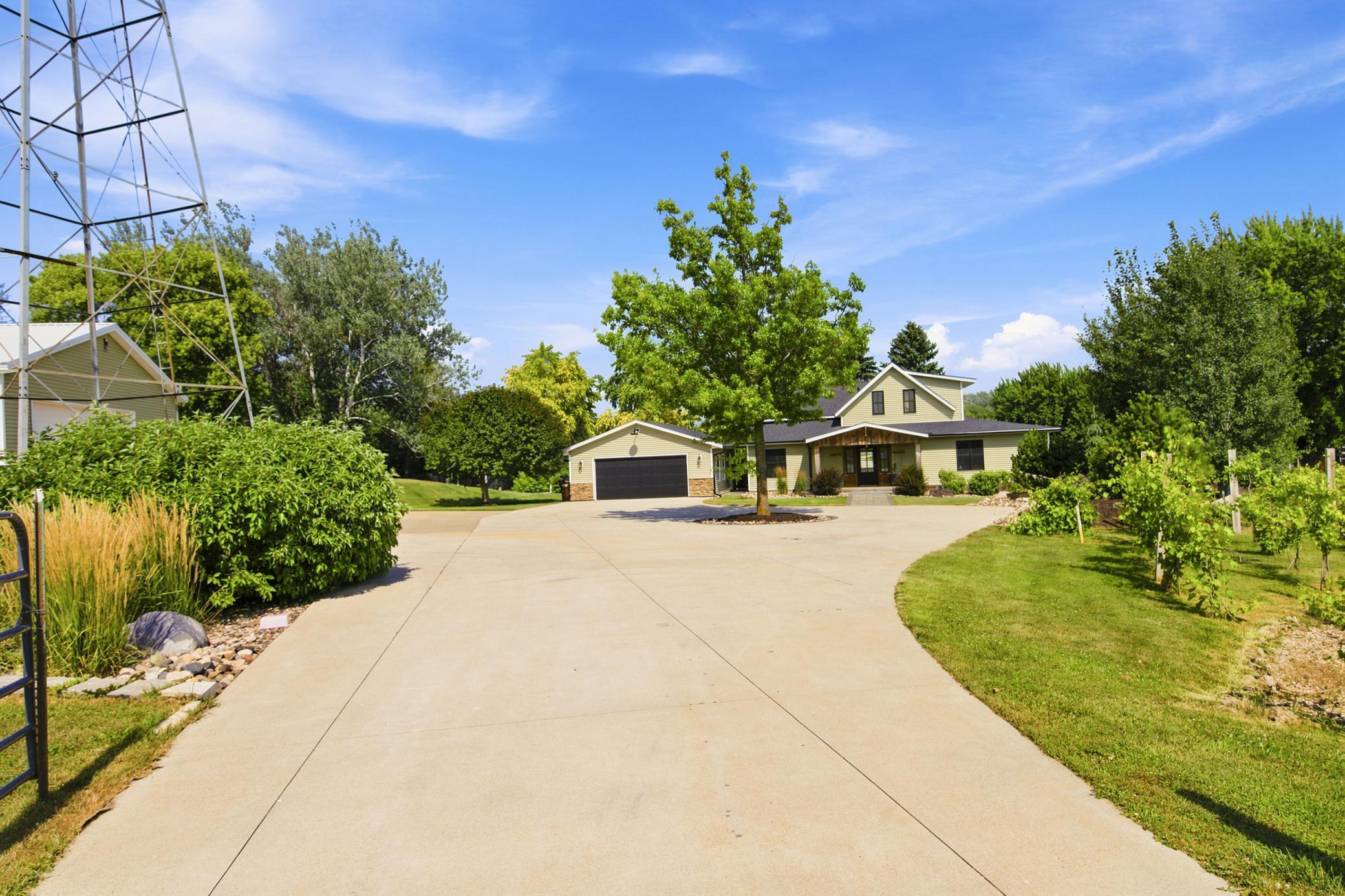 An expansive concrete driveway sweeps past a lush private vineyard and a classic decorative windmill, welcoming you to this stunning home.