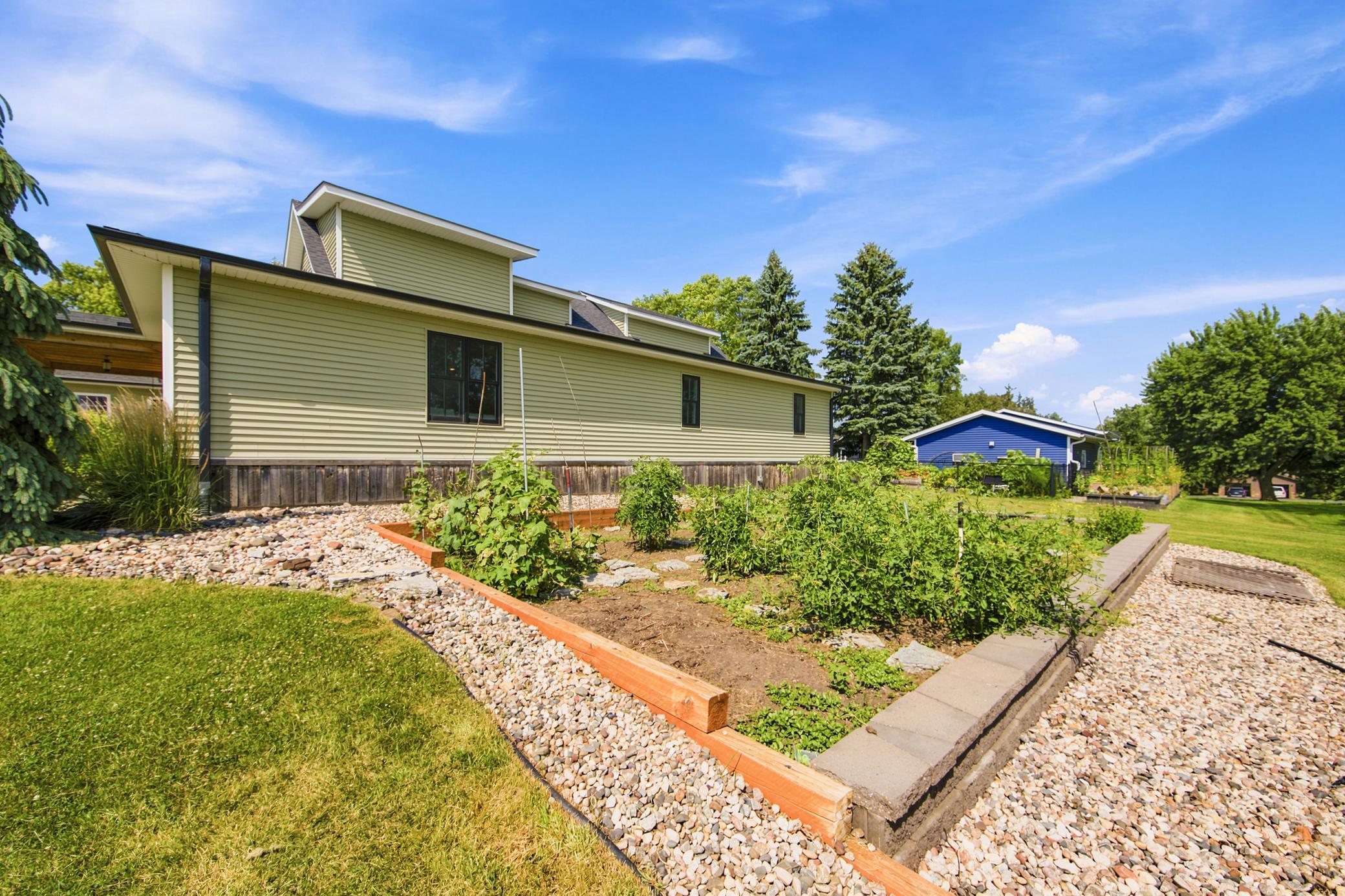 The sprawling property boasts an exceptional backyard setup complete with a large raised-bed garden and its own private, neatly trellised hobby vineyard.