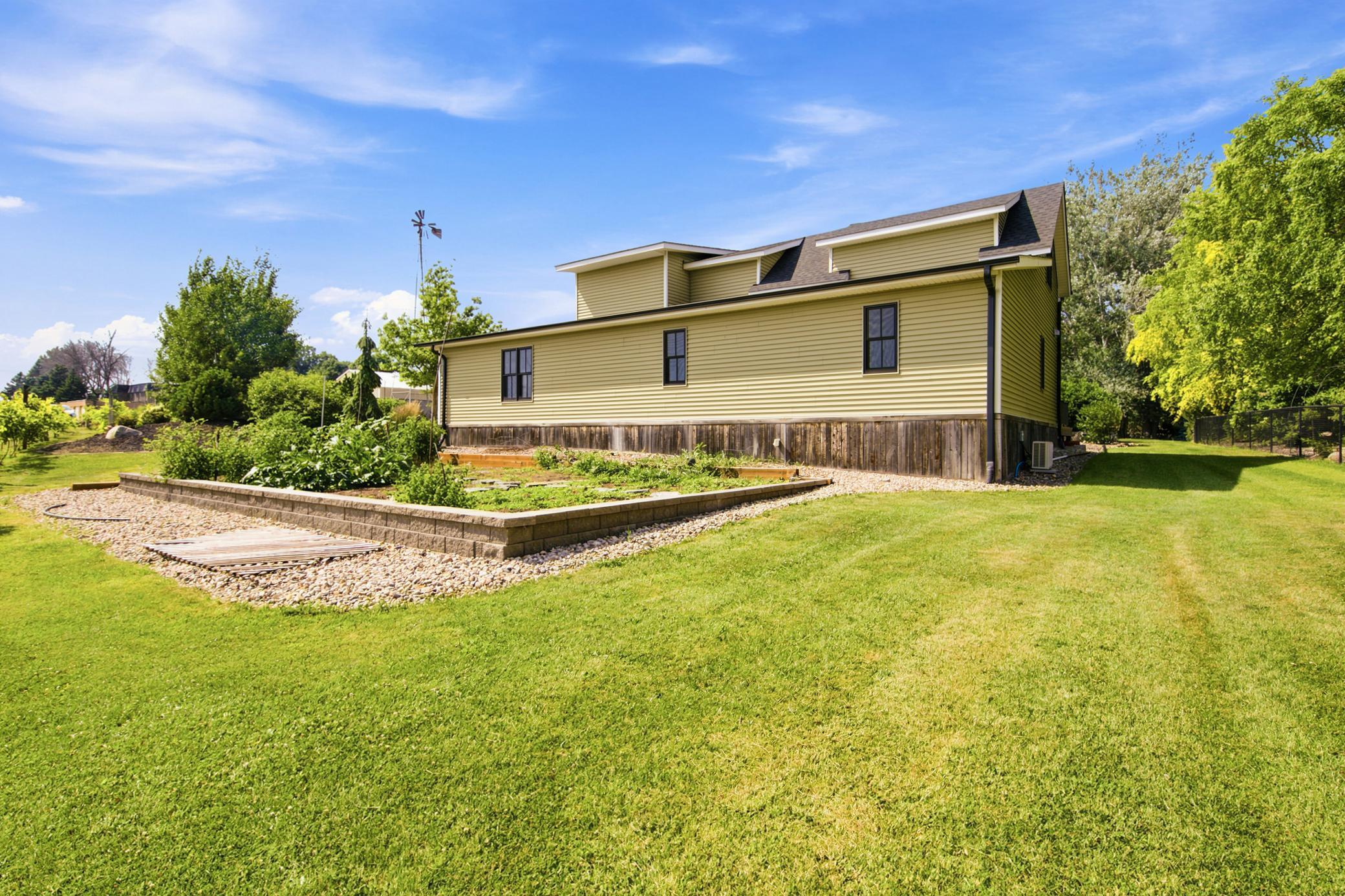 The sprawling property boasts an exceptional backyard setup complete with a large raised-bed garden and its own private, neatly trellised hobby vineyard.