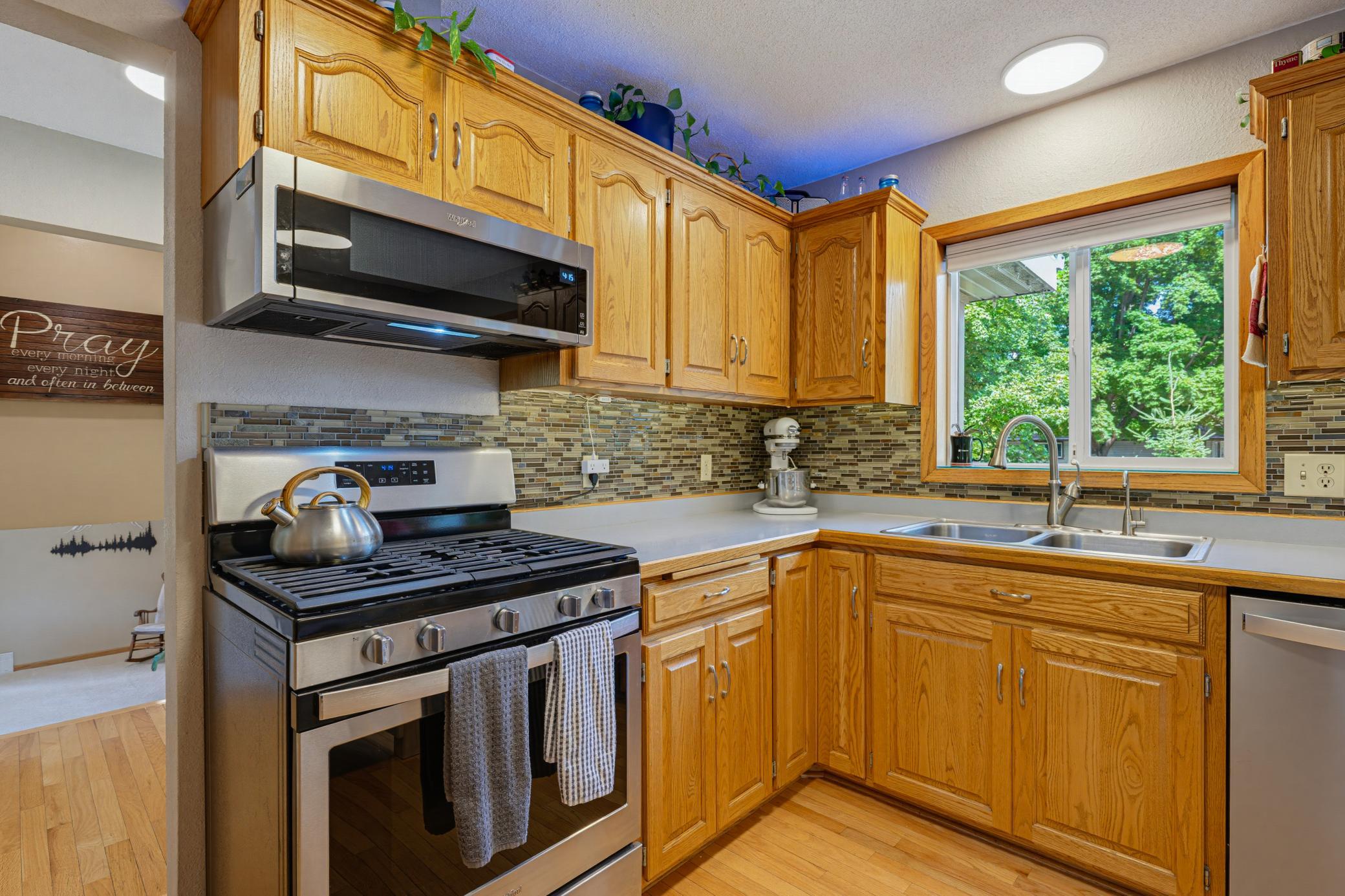 The kitchen features oak cabinets and a tiled backsplash. A window over the kitchen sink provides you with a view of the front yard.