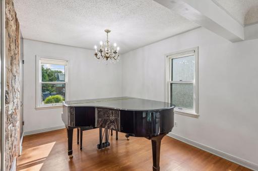 Formal dining room currently used as a piano room, featuring hardwood floors, chandelier and natural light. Flexible space for dining, music, or entertaining.